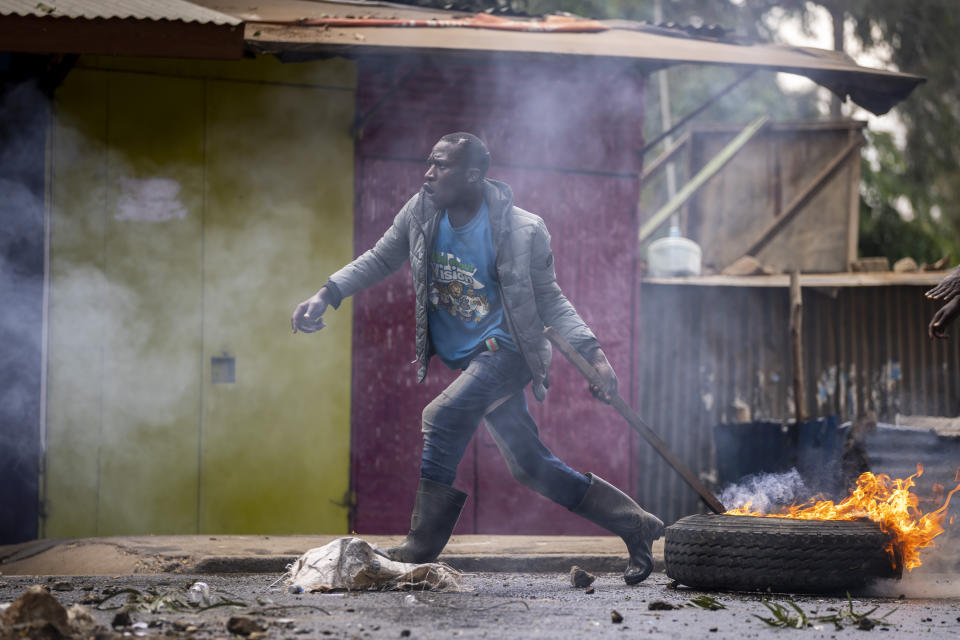 A protester pulls a burning barricade towards police in the Kibera slum of Nairobi, Kenya Monday, March 20, 2023. Hundreds of opposition supporters have taken to the streets of the Kenyan capital over the result of the last election and the rising cost of living, in protests organized by the opposition demanding that the president resigns from office. (AP Photo/Ben Curtis)