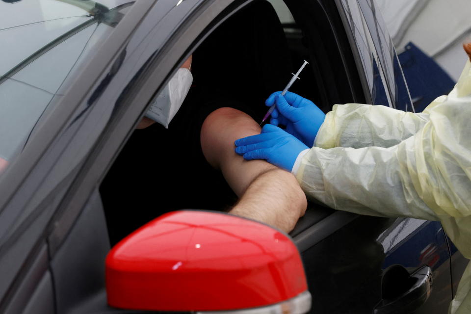 A health worker vaccinates a person with a dose of coronavirus disease (COVID-19) vaccine at the first drive-in vaccination center in Berlin, Germany, February 10, 2022. REUTERS/Michele Tantussi