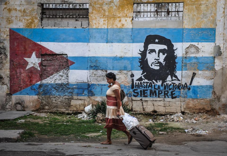 A woman walks by a mural of the Cuban flag and an image of revolutionary leader Ernesto Che Guevara in Havana.