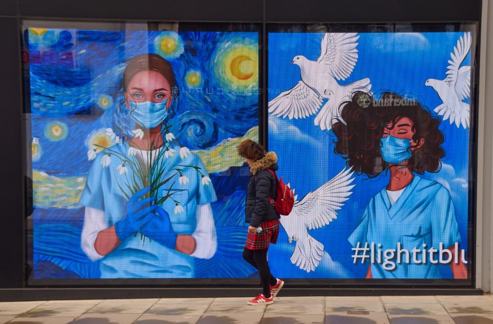 <p>A woman walks past the screens displaying medical workers wearing face masks at the Flannels store on Oxford Street in London. The screens at the store were showing a series of artworks as part of the 'Light It Blue' campaign in support of the NHS during the coronavirus crisis. (Photo by Vuk Valcic / SOPA Images/Sipa USA)</p>
