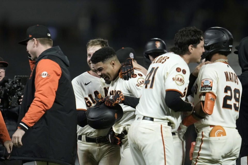 San Francisco Giants' LaMonte Wade Jr., holding helmet, celebrates with teammates after hitting the game-winning RBI single against the Cleveland Guardians during the 10th inning of a baseball game Monday, Sept. 11, 2023, in San Francisco. (AP Photo/Godofredo A. Vásquez)