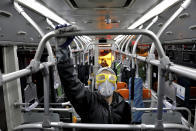 A worker disinfects a public bus against coronavirus in Tehran, Iran, in early morning of Wednesday, Feb. 26, 2020. Iran's government said Tuesday that more than a dozen people had died nationwide from the new coronavirus, rejecting claims of a much higher death toll of 50 by a lawmaker from the city of Qom that has been at the epicenter of the virus in the country. (AP Photo/Ebrahim Noroozi)