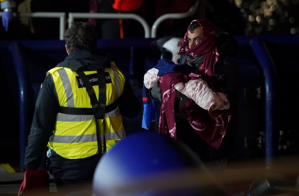 A man carries a baby as a group of people thought to be migrants are brought in to Dover, Kent, after being rescued by the RNLI following a small boat incident in the Channel (Gareth Fuller/PA) (PA Wire)