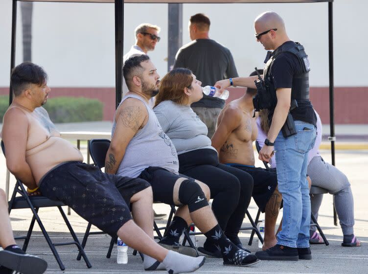 On officer offers water to one of the people detained in an early morning sweep of alleged members of the Quiet Village gang