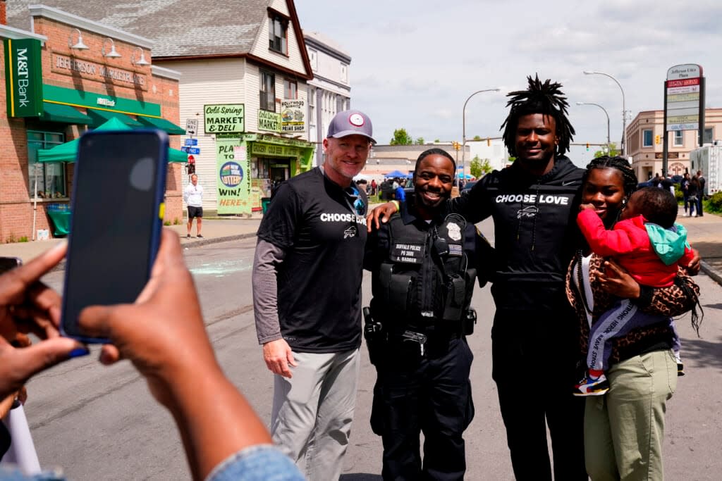 Buffalo Bills’ Josh Thomas, second right, and coach Sean McDermott, center left, poses for a photograph near the scene of Saturday’s shooting at a supermarket, in Buffalo, N.Y., Wednesday, May 18, 2022. (AP Photo/Matt Rourke)