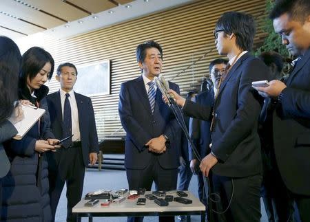 Japan's Prime Minister Shinzo Abe (C) speaks to reporters at his official residence in Tokyo in this photo taken by Kyodo February 7, 2016. REUTERS/Kyodo