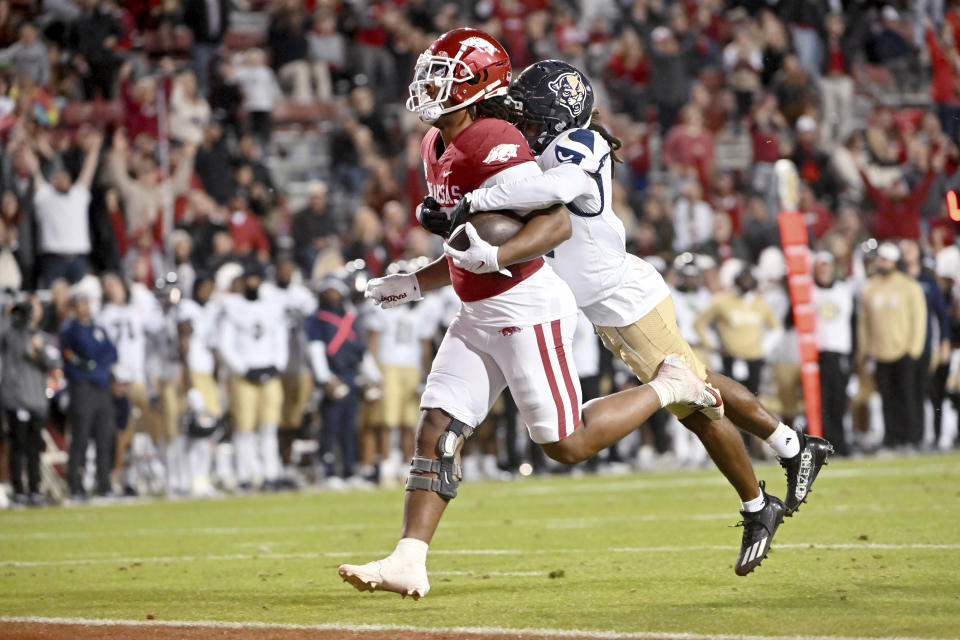 Arkansas running back Dominique Johnson (20) runs for a touchdown as Florida International defensive back Adrian Cole (6) tries to make the tackle during the first half of an NCAA college football game Saturday, Nov. 18, 2023, in Fayetteville, Ark. (AP Photo/Michael Woods)