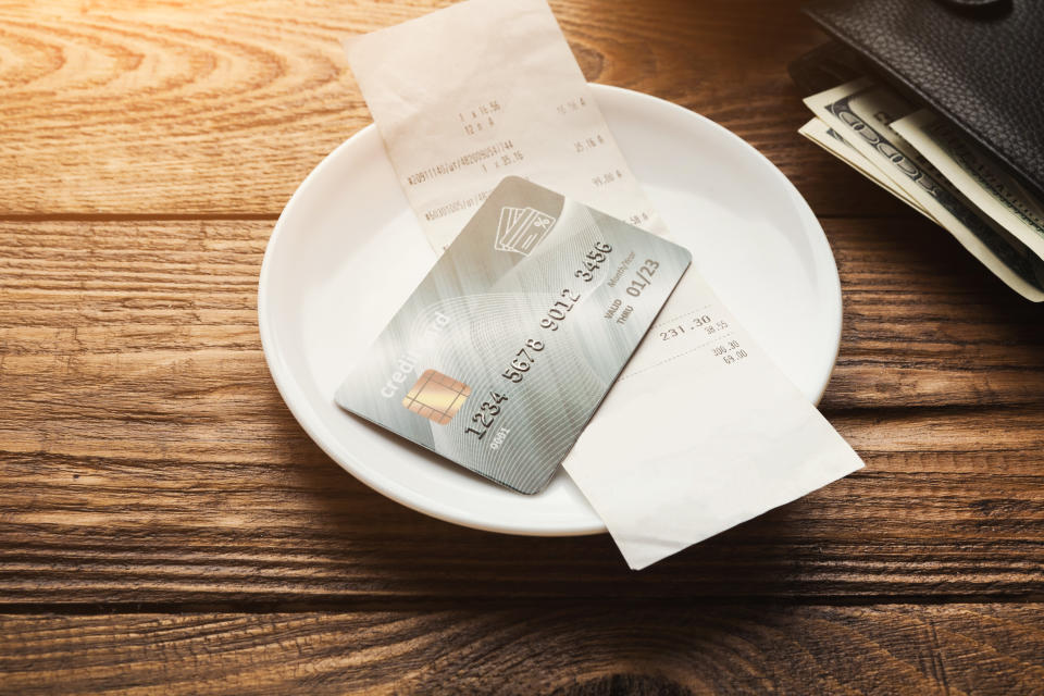 Restaurant bill for coffee and credit card on wooden table, paying for lunch at cafe, copy space