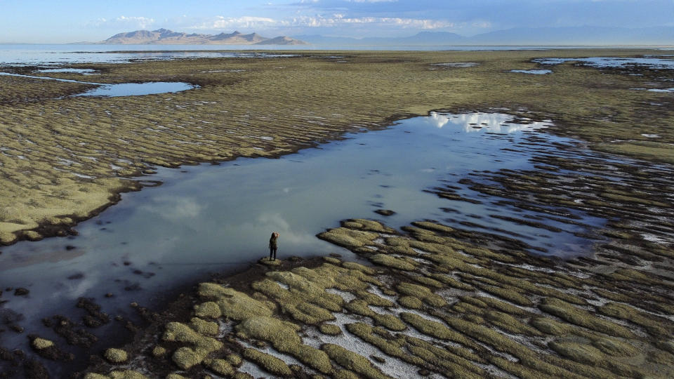 FILE - State of Utah Department of Natural Resources park ranger Angelic Lemmon walks across reef-like structures called microbialites, exposed by receding waters at the Great Salt Lake on Wednesday, Sept. 28, 2022, near Salt Lake City. Amid rising panic about the future of Utah's Great Salt Lake, The Church of Jesus Christ of Latter-day Saints is putting newfound emphasis on environmental stewardship. A high-ranking church official spoke to scientists and politicians at the University of Utah on Friday, March 17, 2023, about the church's recent move to donate 20,000 acre-feet of water to help maintain the elevation of the Great Salt Lake and commitment to re-landscaping its temples and meetinghouses known for their neatly manicured grass. (AP Photo/Rick Bowmer,File)