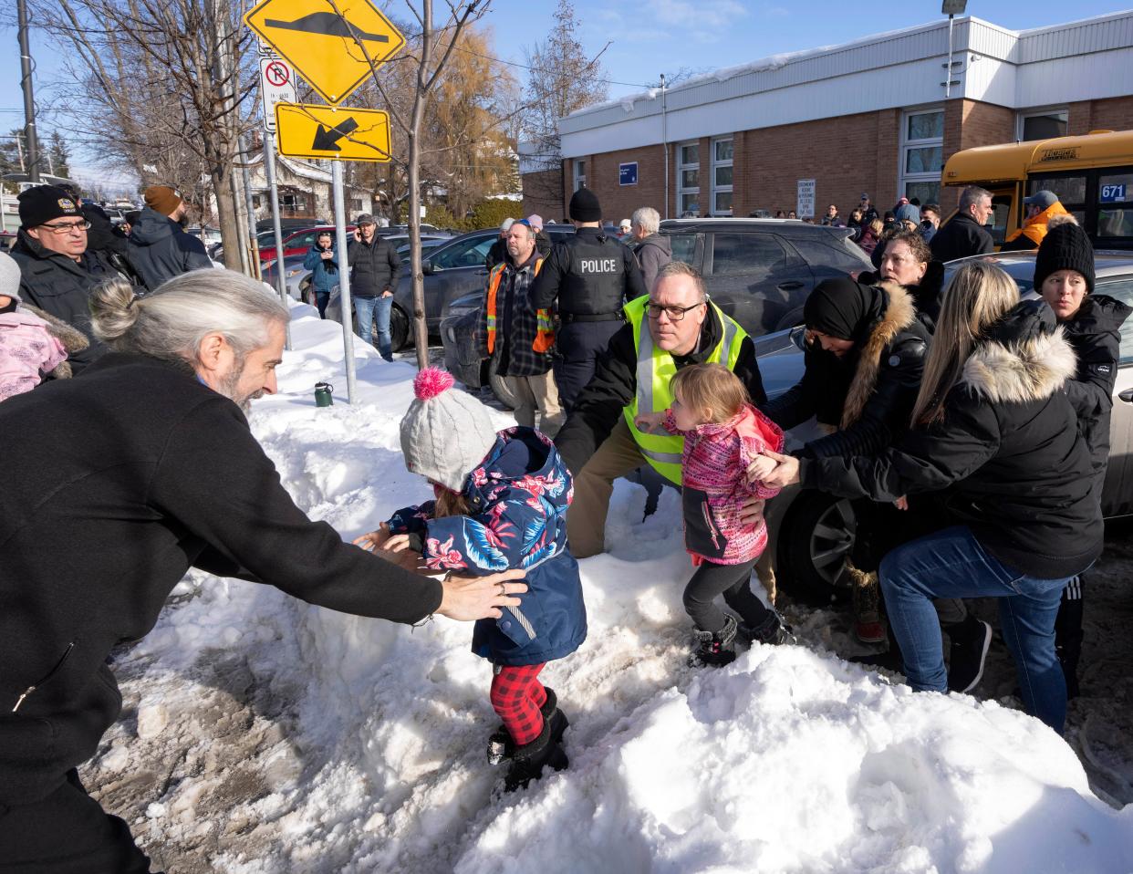 Parents and their children are loaded onto a warming bus as they wait for news after a bus crashed into a daycare centre in Laval, Quebec, on Wednesday, Feb. 8, 2023 (AP)