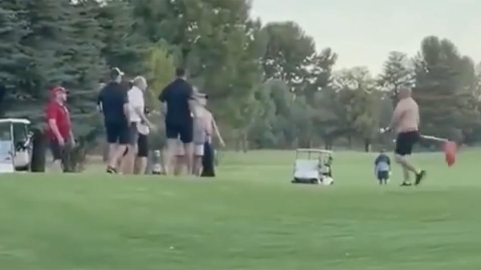 A shirtless man brings a flag to a fist fight during an altercation that broke out on a golf course in South Africa. 