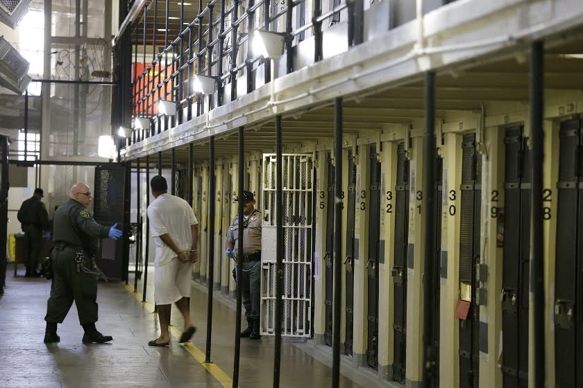 FILE - In this Aug. 16, 2016 file photo, a condemned inmate is led out of his east block cell on death row at San Quentin State Prison in San Quentin, Calif. A California appeals court has ordered state corrections officials to cut the population of one of the world's most famous prisons to less than half of its designed capacity, citing officials' "deliberate indifference" to the plight of inmates during the coronavirus pandemic. State prison officials said Wednesday, Oct. 21, 2020, that they are deciding whether to appeal the order, which otherwise will force them to parole or transfer about 1,100 inmates serving time in San Quentin State Prison north of San Francisco. (AP Photo/Eric Risberg, File)