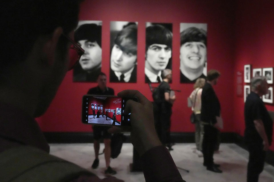 A visitor takes pictures on his phone during a preview of Paul McCartney Photographs 1963-64: Eyes of the Storm exhibition at the National Portrait Gallery in London, Britain, Tuesday, June 27, 2023. The exhibition consists of unseen photographs taken by Paul McCartney from the Beatles at the height of Beatlemania. The gallery will open it's doors from June 28, 2023 until October 1, 2023. (AP Photo/Frank Augstein)