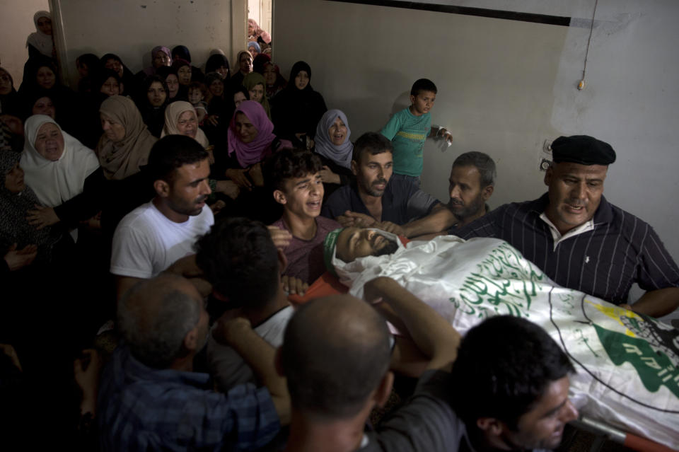 Palestinian mourners carry the body of a Hamas security forces member, Mahmoud al-Adham, 28, into the family home during his funeral in Town of Jabaliya, northern Gaza Strip, Thursday, July 11, 2019. Hamas' armed wing said Thursday that the Israeli army "deliberately" fired at al-Adham, in the northern town of Beit Hanoun. The Israeli military said it noticed two "armed suspects" near the Gaza-Israel perimeter fence and responded with warning shots. (AP Photo/Khalil Hamra)