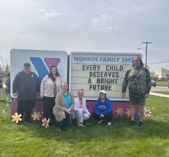 Monroe Family YMCA staff members (from left): Jay Heinzerling, Haleigh Hurley, Penny Marino, Kristin Irwin, Lizzy Stritt and Hawk Mielke are shown in front of the YMCA's sign announcing the Pinwheels for Prevention child abuse awareness campaign, which the YMCA annually offers with the Child Advocacy Network.