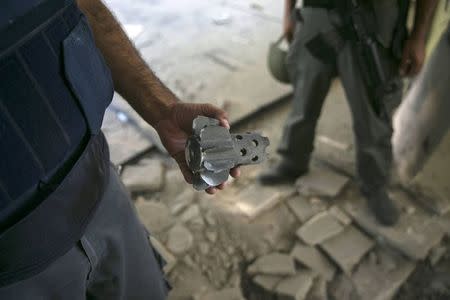 An Israeli police explosives expert shows a remain of a mortar, fired by Palestinian militants in Gaza, after it hit a building in a community outside the central Gaza Strip August 21, 2014. REUTERS/Baz Ratner