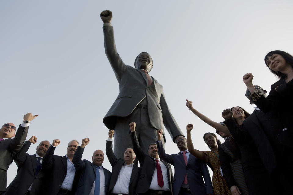 FILE - Palestinians pose at a sculpture of the first democratically elected South African president and anti apartheid leader, the late Nelson Mandela, in the West Bank city of Ramallah. April 26, 2020. South Africa's long-held support for the Palestinian people can be traced back to the time of Mandela and the late Palestinian leader Yasser Arafat with the two leaders believing that the struggle for freedom by Blacks in apartheid South Africa and Palestinians in Gaza and the West Bank were the same. (AP Photo/Nasser Nasser, File)