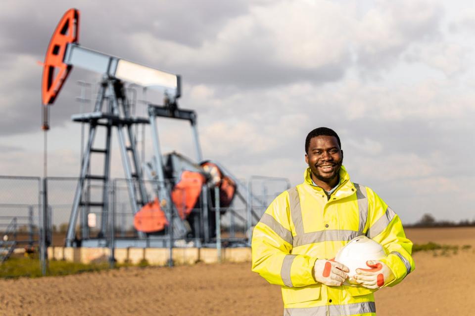 Photo of a worker in front of an oil rig.