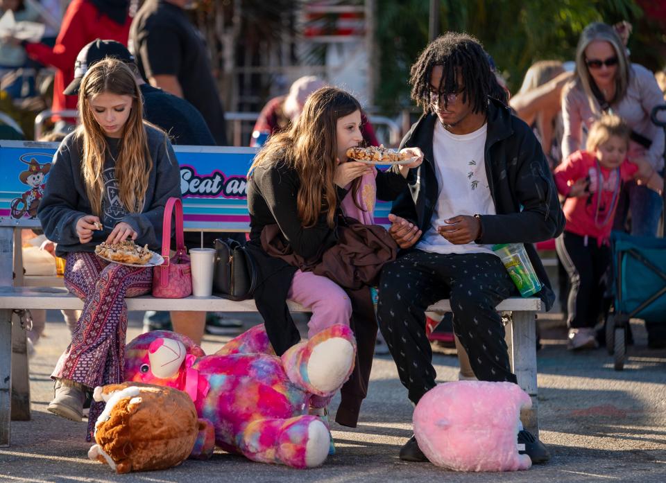 Customers munch on fair food at the South Florida Fair on January 15, 2023.This year's theme is "Dino-Myte'" and  features up to a dozen full-scale, moving, scientifically accurate, animatronic dinosaurs and dinosaur-related exhibits.