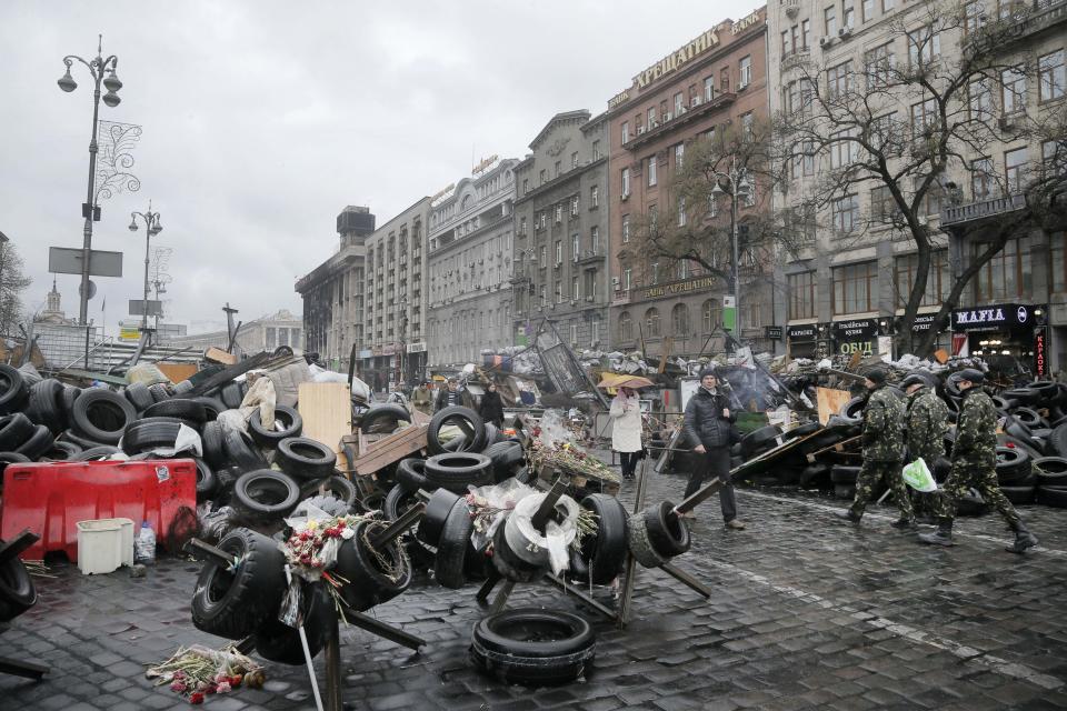 People pass by barricades near the Dnipro Hotel in Kiev, Ukraine, Tuesday, April 1, 2014. A tense standoff between Ukrainian police and a radical nationalist group Right Sector ended Tuesday, when its members surrendered their weapons and left a downtown hotel. Their departure followed a shooting spree in the capital, in which a Right Sector member shot and wounded three people outside a restaurant adjacent to the capital’s main Independence Square, including a deputy mayor of the capital. (AP Photo/Efrem Lukatsky)