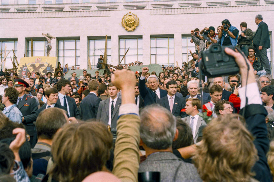 FILE In this Saturday, Aug. 24, 1991 file photo, Russian President Boris Yeltsin, rear right, clenches his fist to express solidarity with the thousands gathered to pay their respects to the victims of the failed Kremlin coup in Moscow, Russia. When a group of top Communist officials ousted Soviet leader Mikhail Gorbachev 30 years ago and flooded Moscow with tanks, the world held its breath, fearing a rollback on liberal reforms and a return to the Cold War confrontation. But the August 1991 coup collapsed in just three days, precipitating the breakup of the Soviet Union that plotters said they were trying to prevent. (AP Photo/Liu Heung Shing, File)