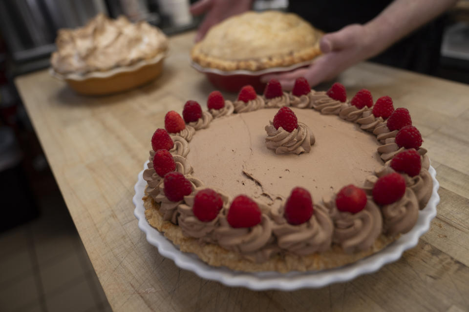 Manager Stephen Jarrett places pies on a counter at Michele's Pies, Wednesday, March 13, 2024, in Norwalk, Conn. Math enthusiasts and bakers celebrate Pi Day on March 14 or 3/14, the first three digits of a mathematical constant with many practical uses. Around the world many people will mark the day with a slice of sweet or savory pie. (AP Photo/John Minchillo)