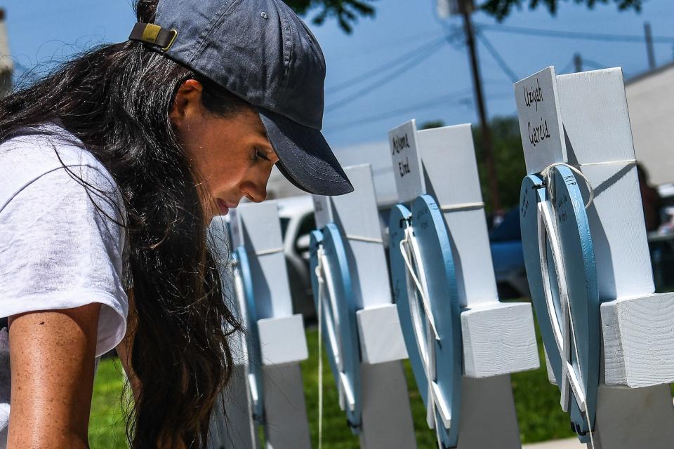 TOPSHOT - Meghan Markle, the wife of Britain's Prince Harry, places flowers as she mourns at a makeshift memorial outside Uvalde County Courthouse in Uvalde, Texas, on May 26, 2022. - Grief at the massacre of 19 children at the elementary school in Texas spilled into confrontation on May 25, as angry questions mounted over gun control -- and whether this latest tragedy could have been prevented. The tight-knit Latino community of Uvalde on May 24 became the site of the worst school shooting in a decade, committed by a disturbed 18-year-old armed with a legally bought assault rifle. (Photo by CHANDAN KHANNA / AFP) (Photo by CHANDAN KHANNA/AFP via Getty Images)