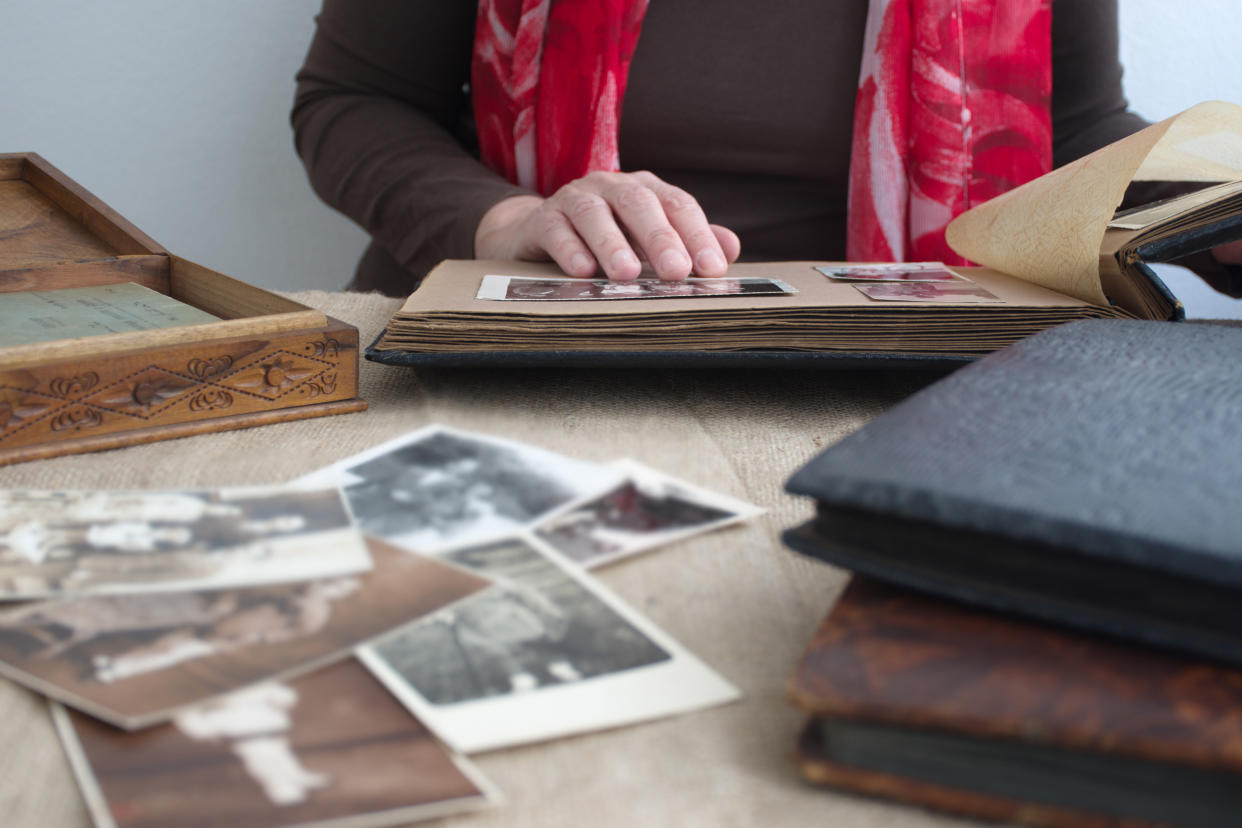 Midsection of woman holding old retro photo album with vintage monochrome photographs in sepia color