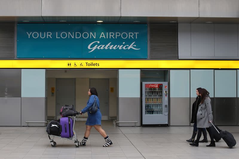 FILE PHOTO: Travellers pass a sign for Gatwick Airport in southern Britain