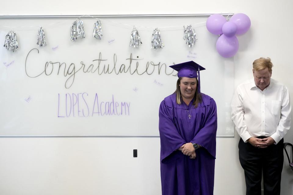 Apr 28, 2023; Phoenix, Ariz., U.S.;  Emma Cardon, a participant in the LOPES Academy, a nondegree program for individuals with intellectual and developmental disabilities, received a completion certificate during Grand Canyon's 2023 commencement ceremony. Cardon says a prayer during the reception. To her right is GCU's Dean of Humanities and Social Sciences Sherman Elliott.