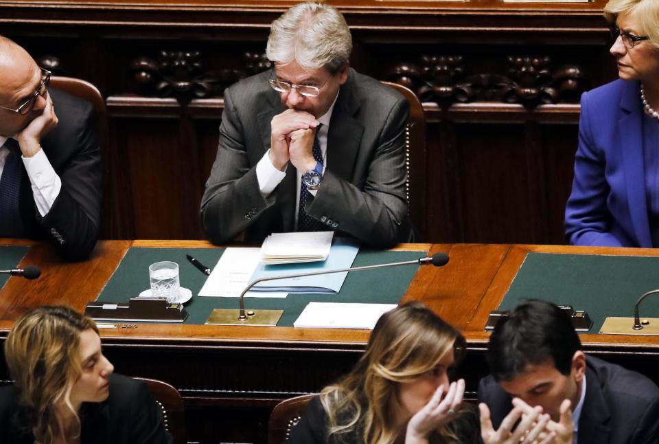 Italian Prime Minister Paolo Gentiloni, center, sits surrounded by members of his government, from left counter clock-wise, Foreign Minister Angelino Alfano, Public Function and Simplification Minister Marianna Madia, Undersecretary Maria Elena Boschi, Agriculture Minister Maurizio Martina, and Defense Minister Roberta Pinotti, before asking a confidence vote at the Parliament's lower house, in Rome Tuesday, Dec. 13, 2016. Paolo Gentiloni, a Democrat formerly serving as foreign minister, formed Italy’s new government Monday, keeping several key ministers from the coalition of Matteo Renzi, who resigned last week. (AP Photo/Alessandra Tarantino)