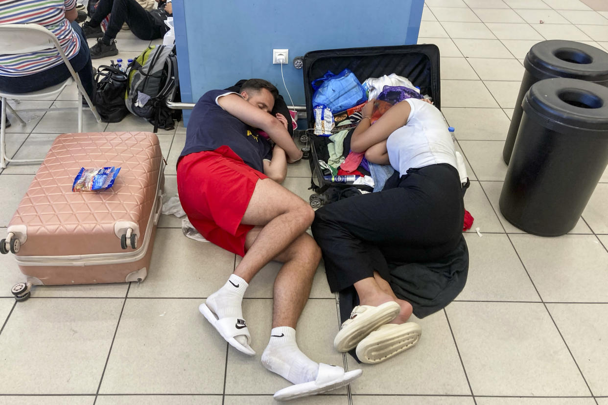 Tourists rest as they wait in the airport's departure hall as evacuations are underway due to wildfires, on the Greek island of Rhodes on July 23, 2023. Locals and tourists fled hotspots on Rhodes, as firefighters battled a blaze that had sparked the country's largest-ever fire evacuation. Firefighters were bracing for high winds that have been forecast for the afternoon and that could hamper their efforts. (Photo by Will VASSILOPOULOS / AFP) (Photo by WILL VASSILOPOULOS/AFP via Getty Images)