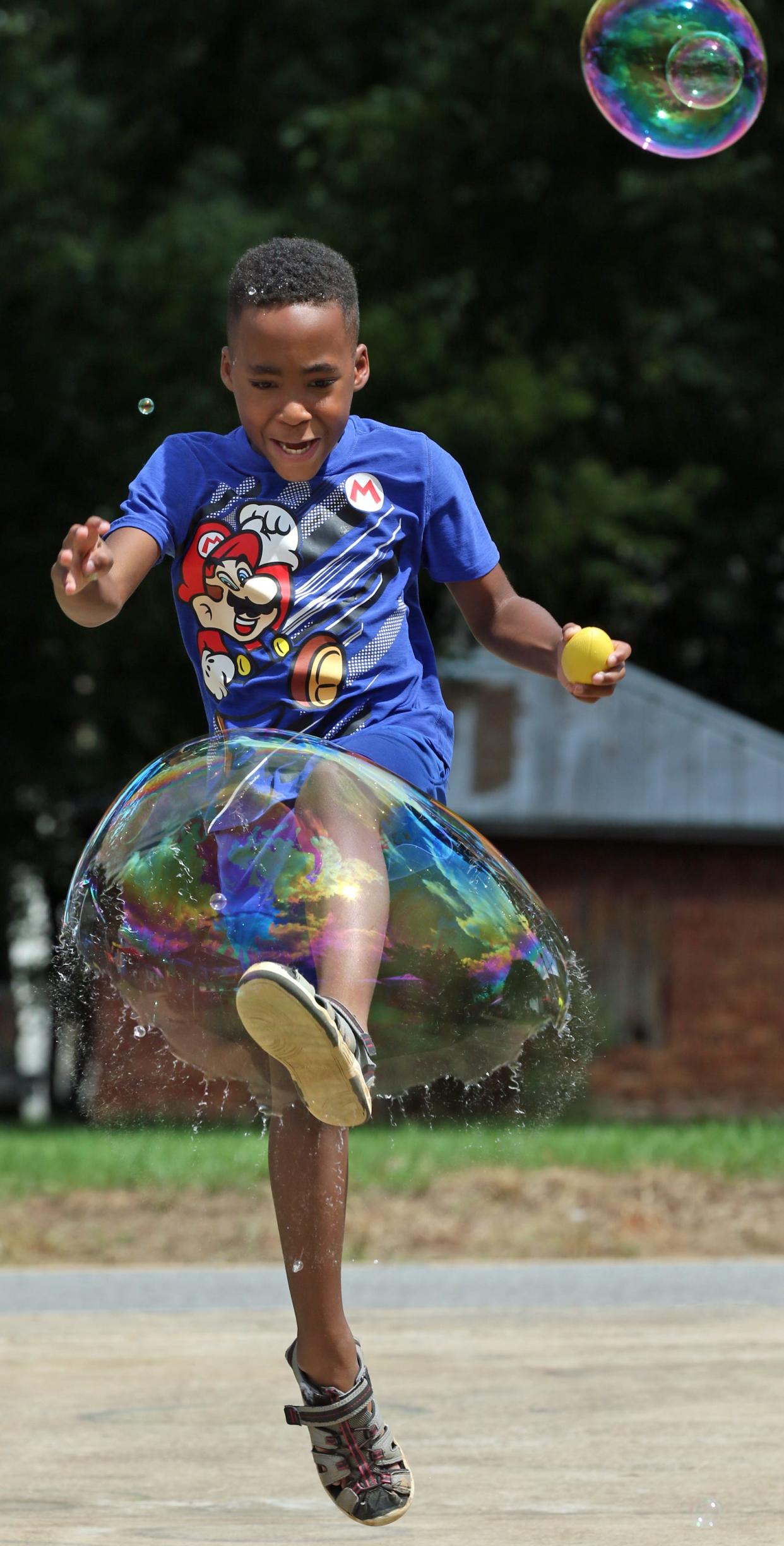 Seven-year-olds Golden McKinney kicks and breaks a big bubble during the annual Kings Mountain Beach Blast Saturday afternoon, August 20, 2022, at Patriots Park.