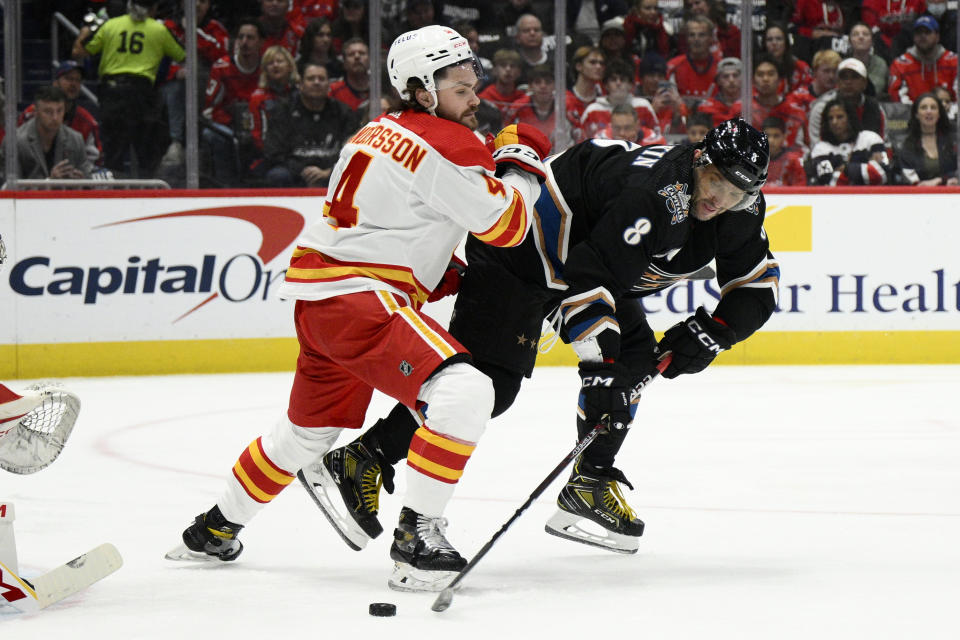 Washington Capitals left wing Alex Ovechkin (8) battles for the puck against Calgary Flames defenseman Rasmus Andersson (4) during the first period of an NHL hockey game, Friday, Nov. 25, 2022, in Washington. (AP Photo/Nick Wass)