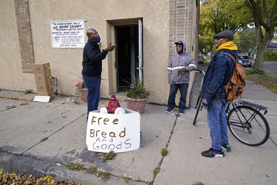 New Mount Calvary Baptist Church members Marles Cooper, left, and Deacon Will visit with DuWayne Evans, right, who rode up on his bicycle and picked up a piece of pie from the church food shelf Thursday, Oct. 1, 2020, in North Minneapolis. In addition to the food shelf, Bishop Divar L. Bryant Kemp makes a plea year-round to both his congregants and others outside of his church to get out and vote, emphasizing the efforts of past civil rights leaders that fought for Black citizens to receive that right. (AP Photo/Jim Mone)