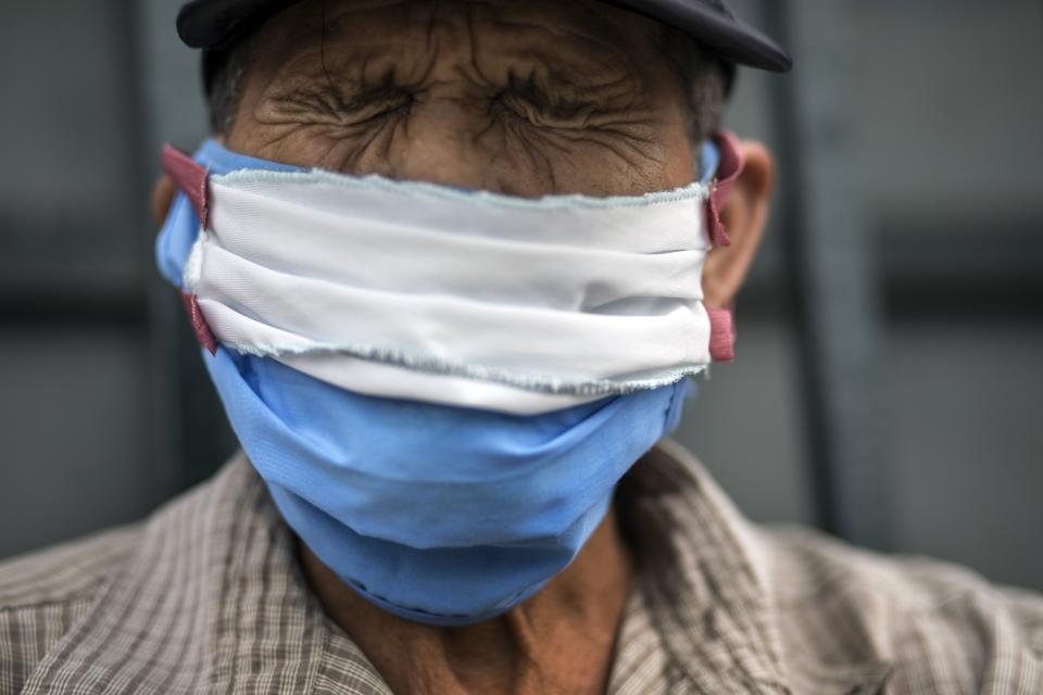 Julio Morales, 72, wearing a self-made face mask amid the spread of the new coronavirus, winces from arthritic pain as he waits to sign up for a place to sleep outside the Plaza de Toros de Acho bullfighting ring in Lima, Peru, Tuesday, March 31, 2020. (AP Photo/Rodrigo Abd)