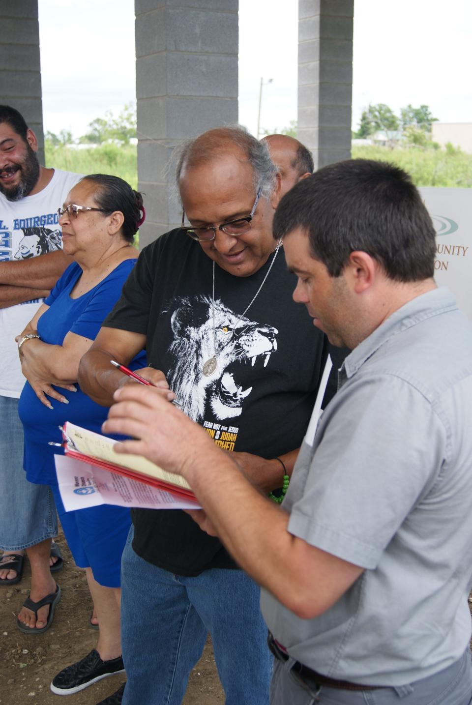 Nathan Trosclair of Dulac and Elvin Shirk sign the paperwork to transfer the home built by Mennonite Disaster Services to Billiot on Wednesday, June 1, 2022.