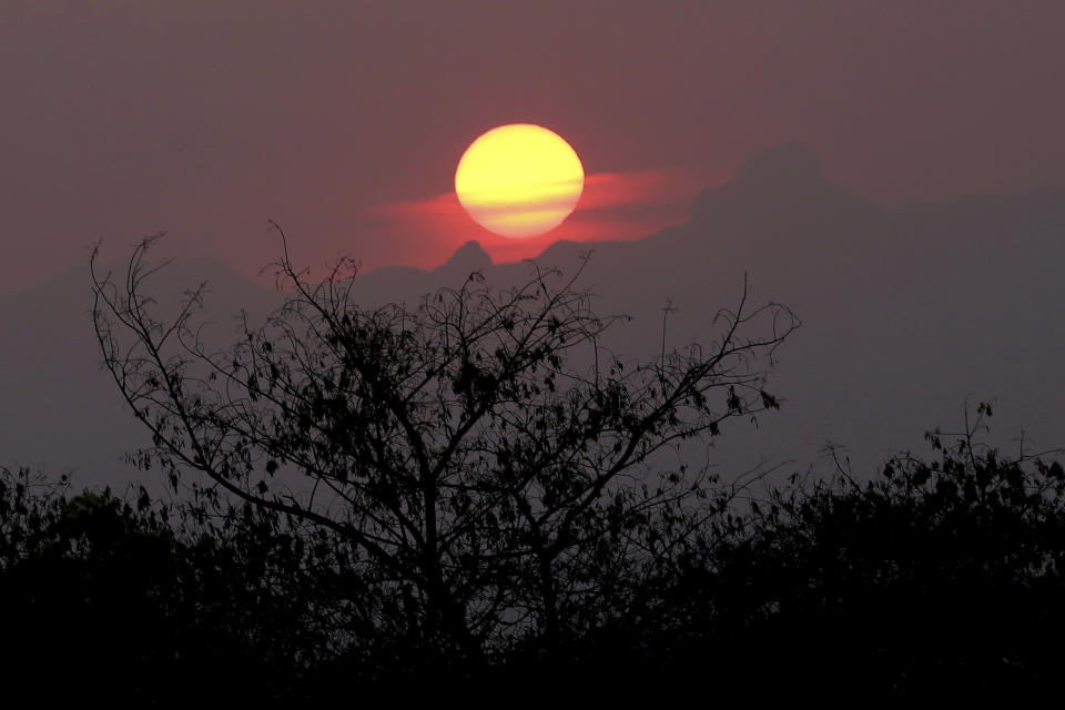 In this Oct. 23, 2018, photo, the sun sets over Fatukoko village in West Timor, Indonesia. The region is one of the driest parts of Indonesia, making farming difficult. Many villagers thus migrate to neighboring Malaysia in search of work. (AP Photo/Tatan Syuflana)