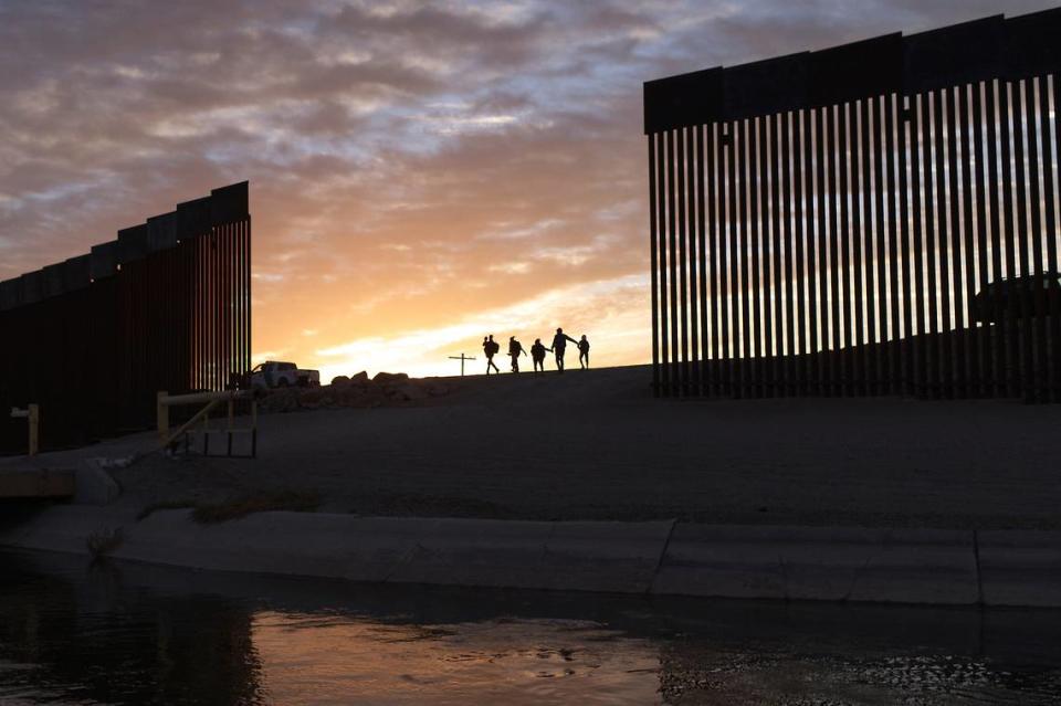 FILE - In this Thursday, June 10, 2021, file photo, a pair of migrant families from Brazil pass through a gap in the border wall to reach the United States after crossing from Mexico to Yuma, Ariz., to seek asylum. The U.S. government has put an end to two Trump administration policies that made it harder for immigrants fleeing violence to qualify for asylum. Attorney General Merrick Garland said Wednesday, June 16, 2021, that immigration judges should no longer follow the rules that made it difficult for immigrants who faced domestic or gang violence to win asylum. (AP Photo/Eugene Garcia, File)