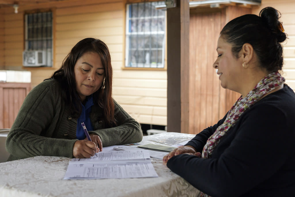 Two women go through federal benefit application forms.