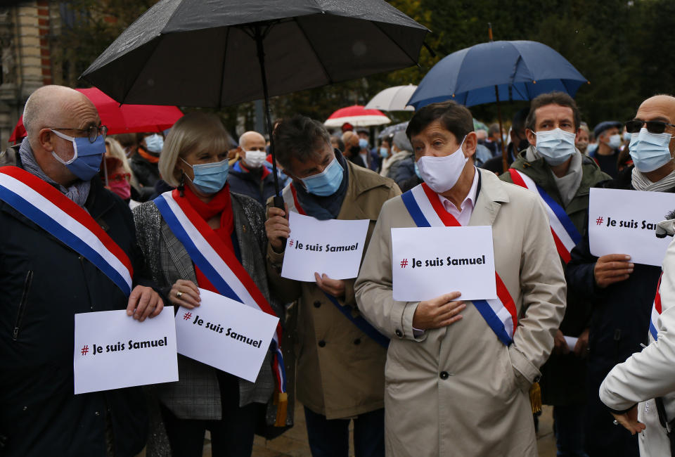 Communist party parliament member Fabien Roussel, third left, and his deputy stand with posters that read: "I am Samuel", as people gather on Republique square in Lille, northern France, Sunday Oct. 18, 2020. Demonstrators in France on Sunday took part in gatherings in support of freedom of speech and in tribute to a history teacher who was beheaded near Paris after discussing caricatures of Islam’s Prophet Muhammad with his class. (AP Photo/Michel Spingler)