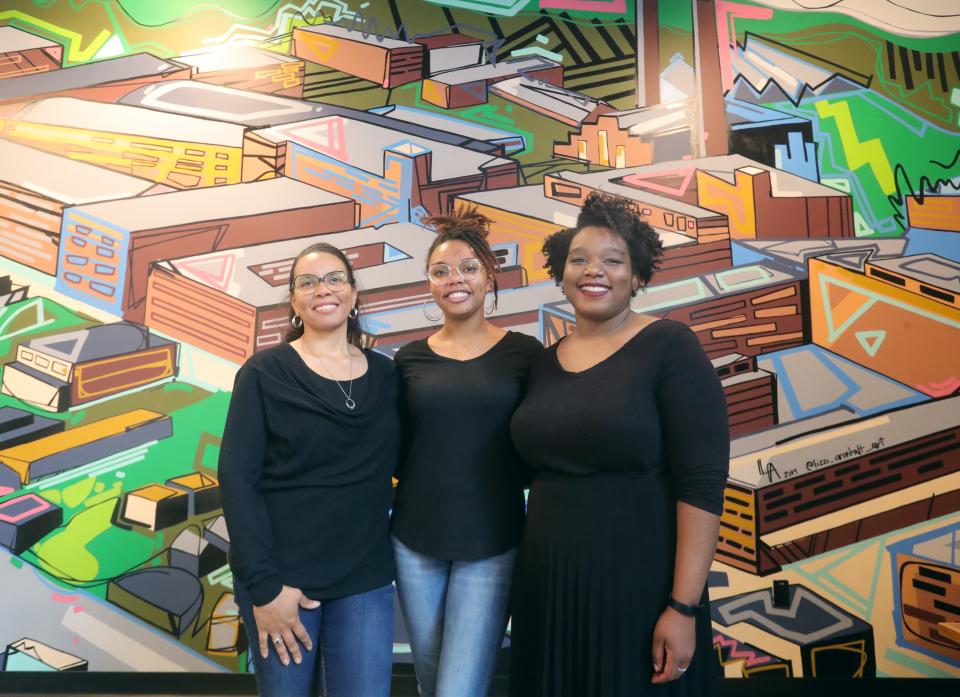 Artists Stephanie Stewart, Kayla Stewart and Talia Hodge stand in front of a mural last Tuesday at the Bounce Innovation Hub in Akron.