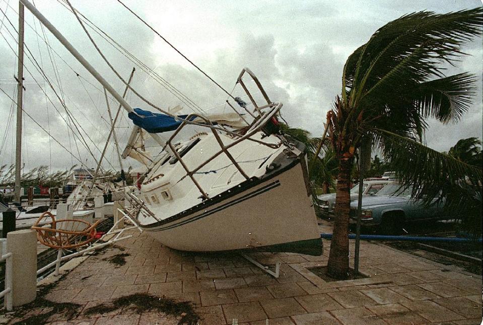 FILE - In this Aug. 24, 1992 file photo, a sailboat sits on a sidewalk at Dinner Key in Miami after it was washed ashore by Hurricane Andrew. Global warming is rapidly turning America into a stormy and dangerous place, with rising seas and disasters upending lives from flood-stricken Florida to the wildfire-ravaged West, the National Climate Assessment concluded Tuesday, May 6, 2014. (AP Photo/Terry Renna, File)