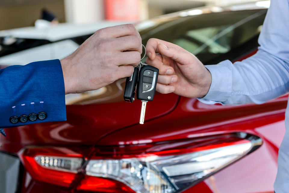 Dealer giving keys to customer in showroom