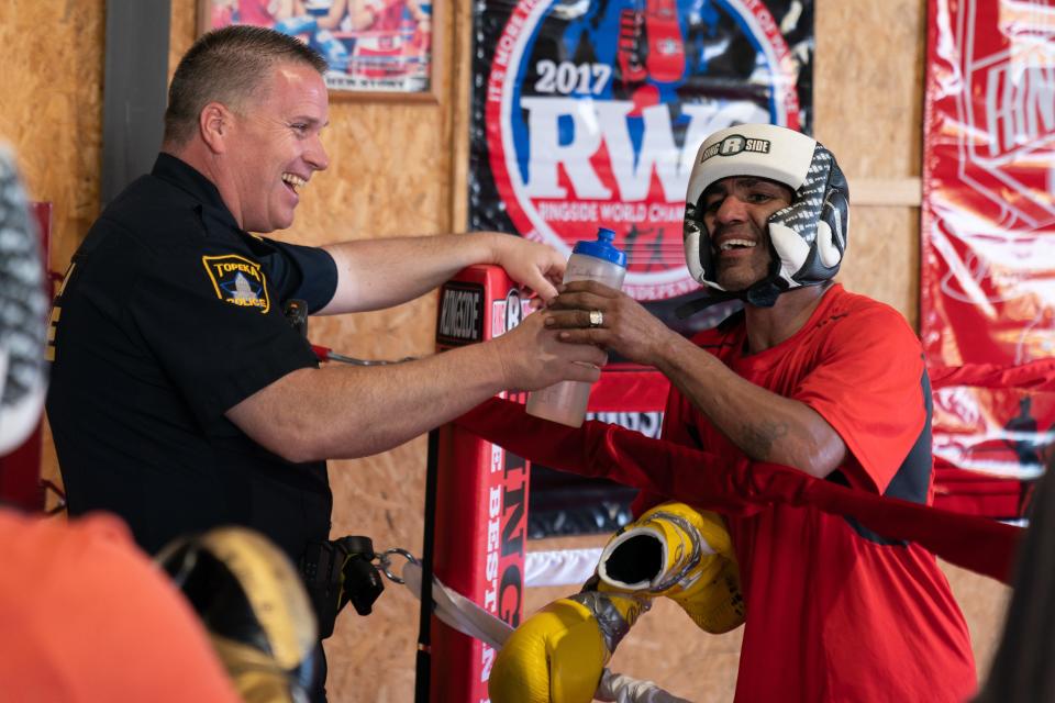 Darren Campbell, a school resource officer for the Topeka Police Department at French Middle School, laughs with Three Shields Boxing Academy trainer and longtime competitor Derrick Campos during a short break in between sparring sessions.