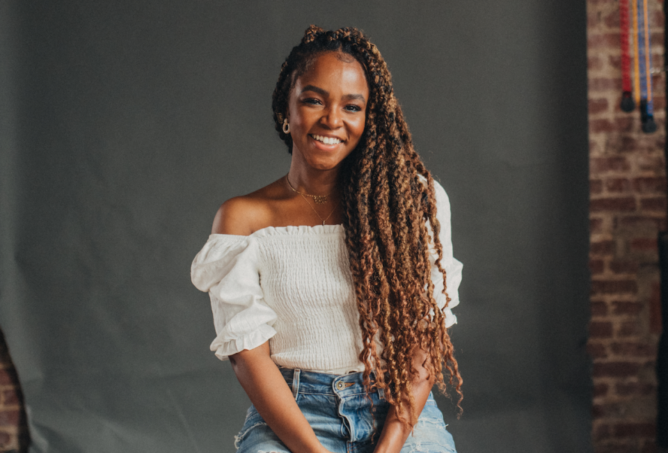 gia peppers smiling in a white blouse and denim jeans