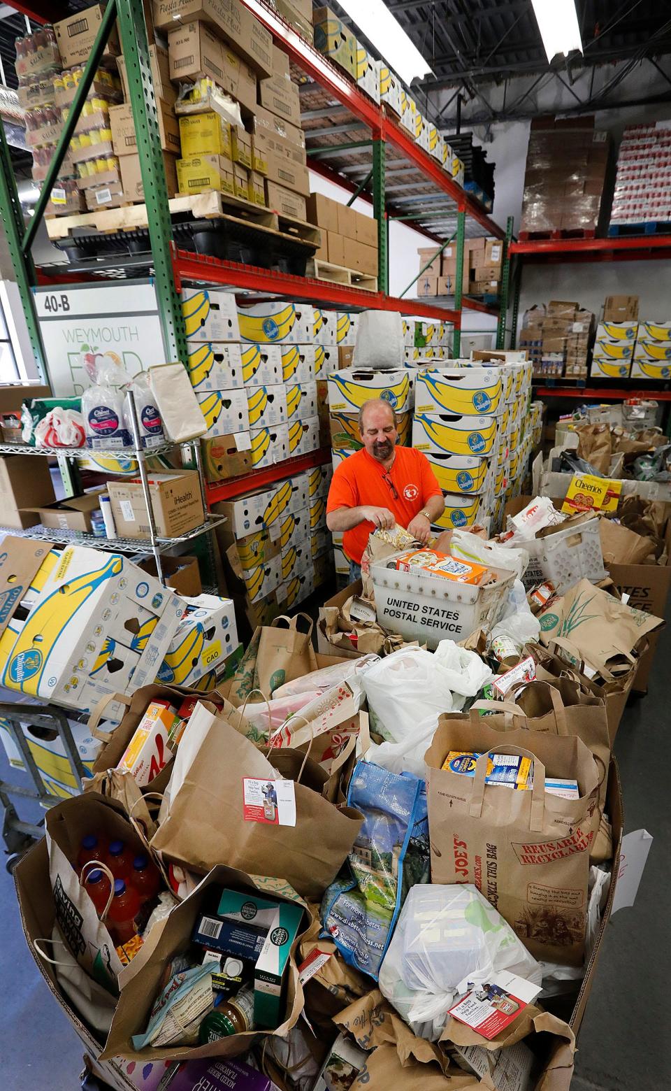Weymouth/Rockland Food Pantry staff member Steve Manupelli,  on Tuesday, May 17, 2022, sorts food collected by United States Postal Service letter carriers in Weymouth.