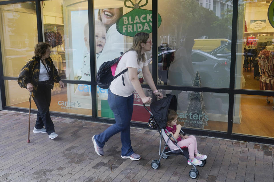 Shoppers looking for bargains walk by a Carter's children's clothing store, Monday, Nov. 21, 2022, in Miami, Fla. Bargain hunting is back with full force heading into the holidays. But inflation is limiting how much of a deal consumers will be getting. (AP Photo/Marta Lavandier)