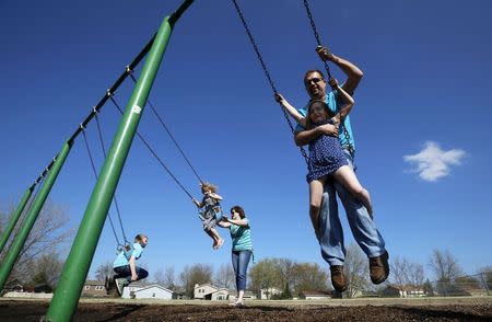 Joe Smith rides on a swing with his daughter Rowan as his wife Andrea plays with her children Norah and Chase at a playground in Winthrop Harbor, Illinois, May 9, 2014. REUTERS/Jim Young