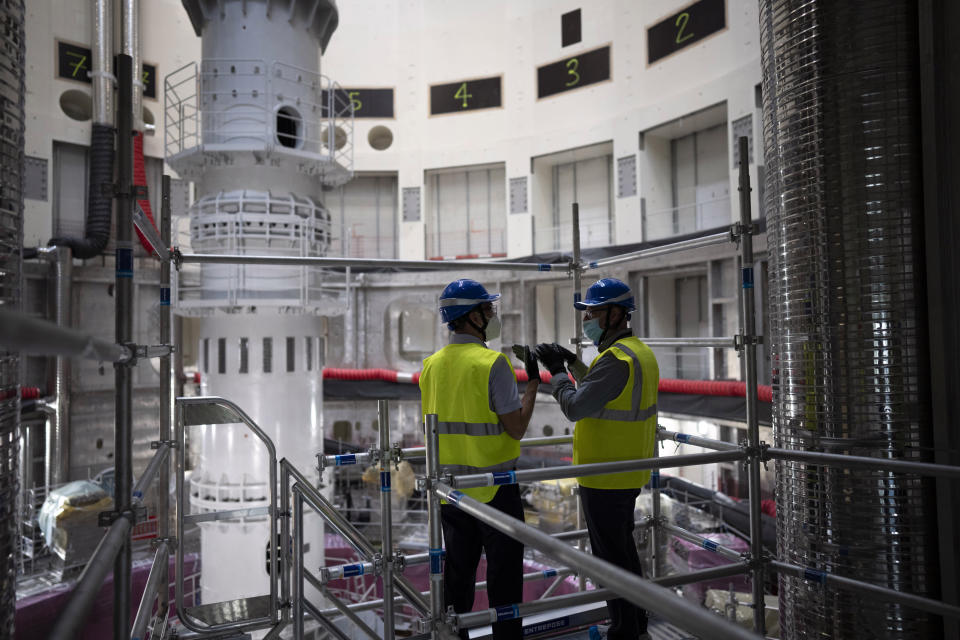 Workers speak together inside the ITER Tokamak machine in Saint-Paul-Lez-Durance, France, Thursday, Sept. 9, 2021. Scientists at the International Thermonuclear Experimental Reactor in southern France took delivery of the first part of a massive magnet so strong its American manufacturer claims it can lift an aircraft carrier. (AP Photo/Daniel Cole)